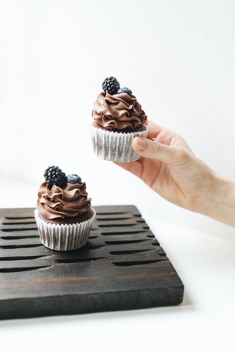 Photo Of Person Holding Chocolate Cupcake With Blackberry On Top